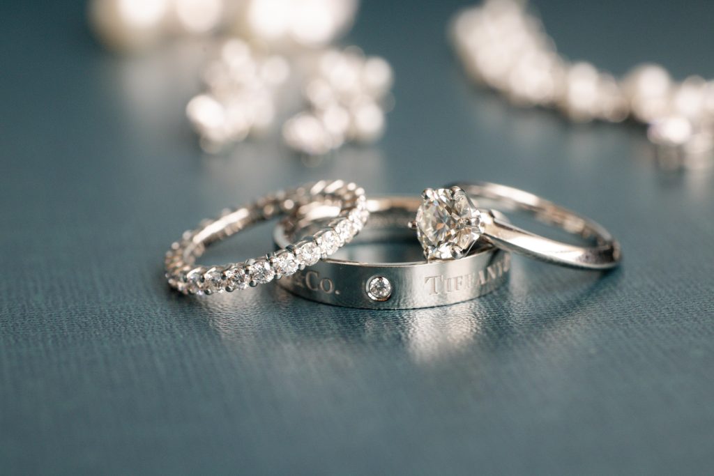 A diamond studded ring, a ring with a diamond in the center, and a Tiffany and Co. ring.