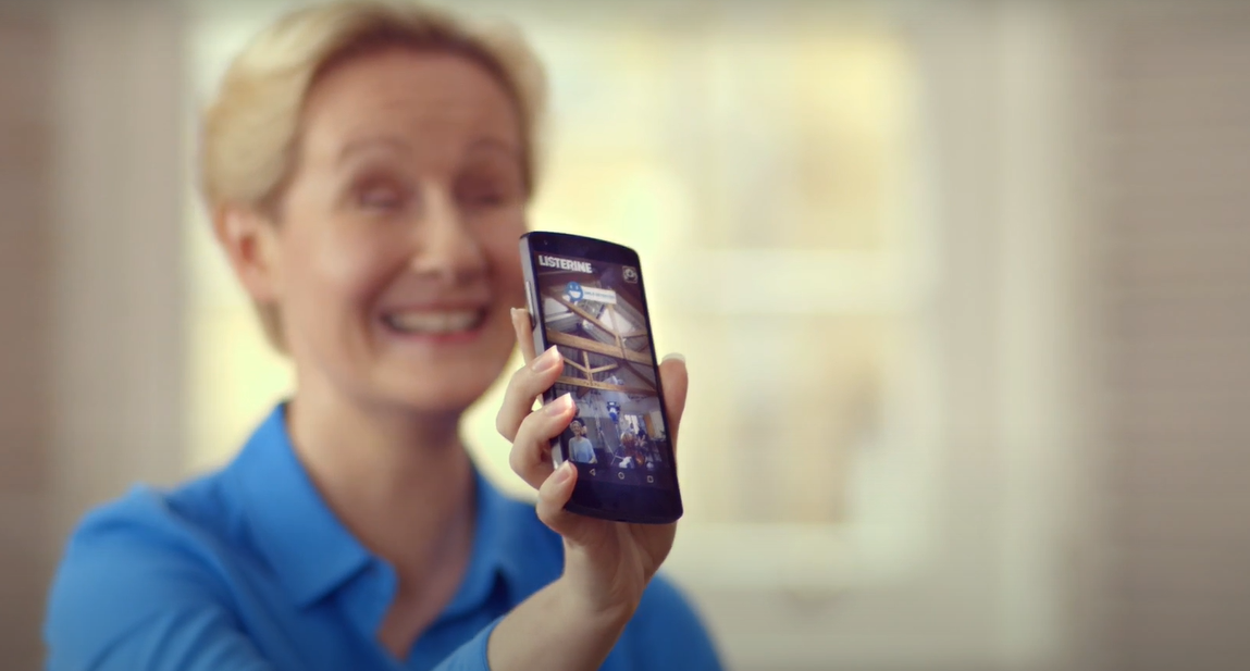 Mulher sorrindo com celular na mão, campanha reconhecimento facial listerine