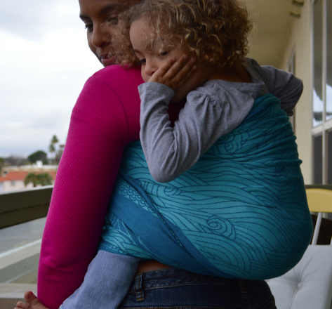 Image of beautiful woman wearing a wrap baby carrier with a toddler