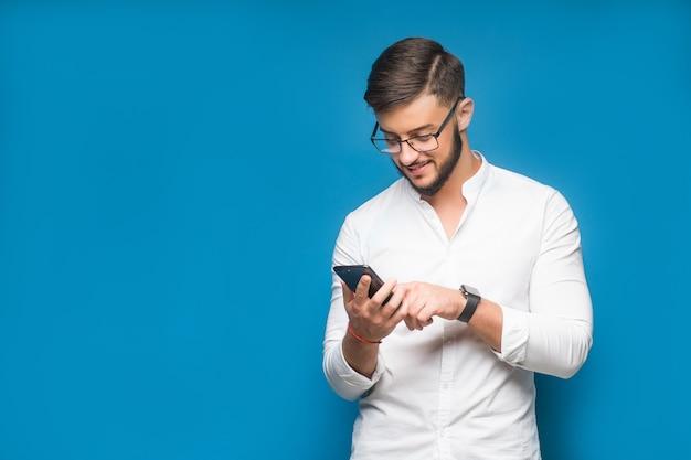 Foto grátis homem de negócios usando aplicativos de celular enviando mensagens de texto no azul