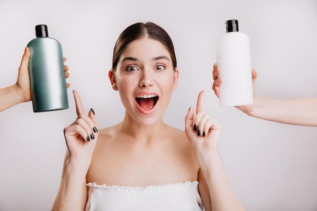 Closeup portrait of joyful girl posing without makeup on white wall. woman chose which shampoo is best to use. Free Photo
