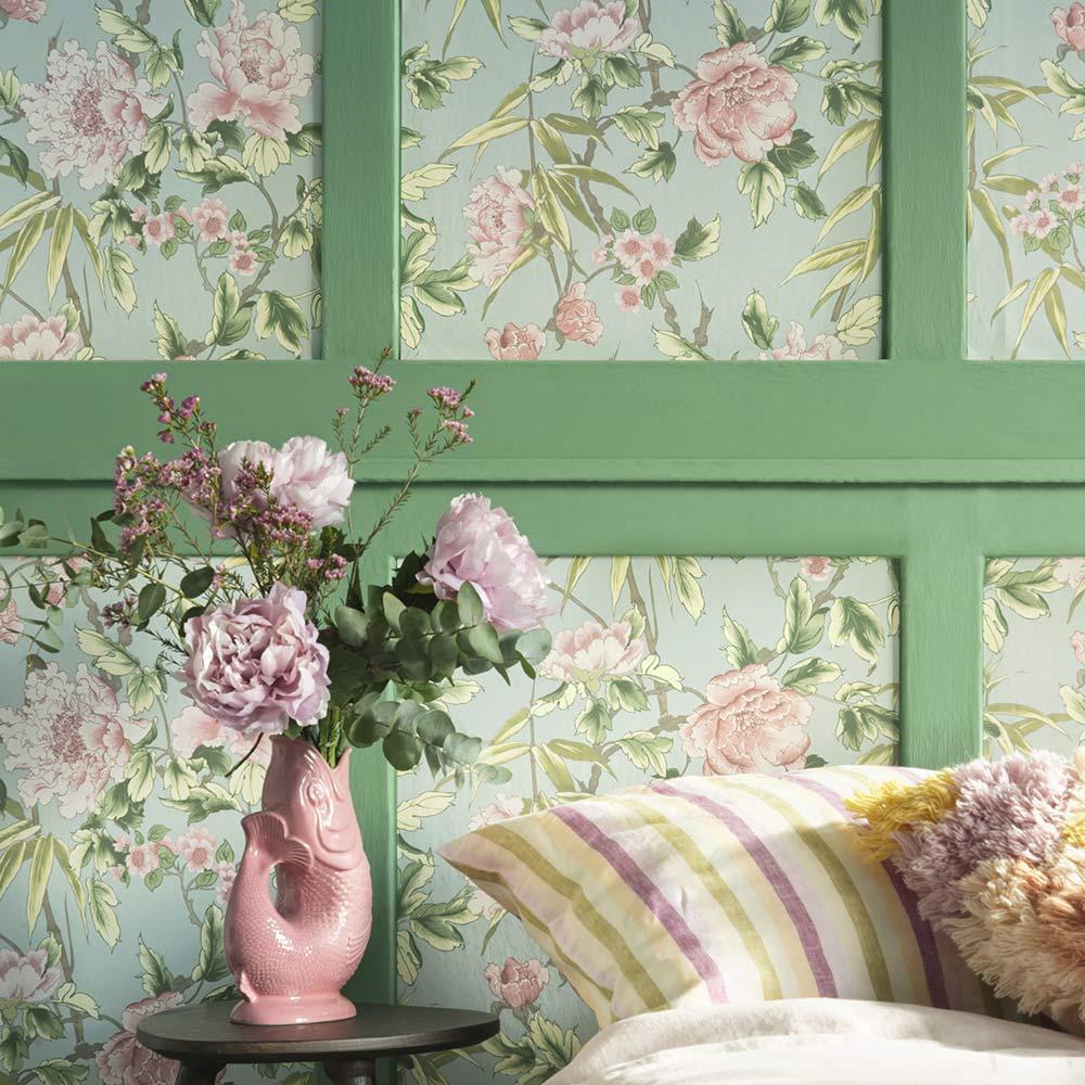ورق حائط اخضر مع ورود وردية امام مزهرية وردية بالورود