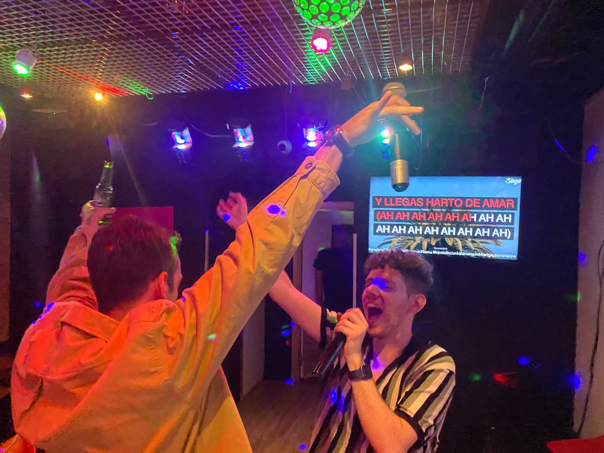 Kaksi miestä vastakkain laulamassa espanjalaista laulua suomalaisessa karaokebaarissa