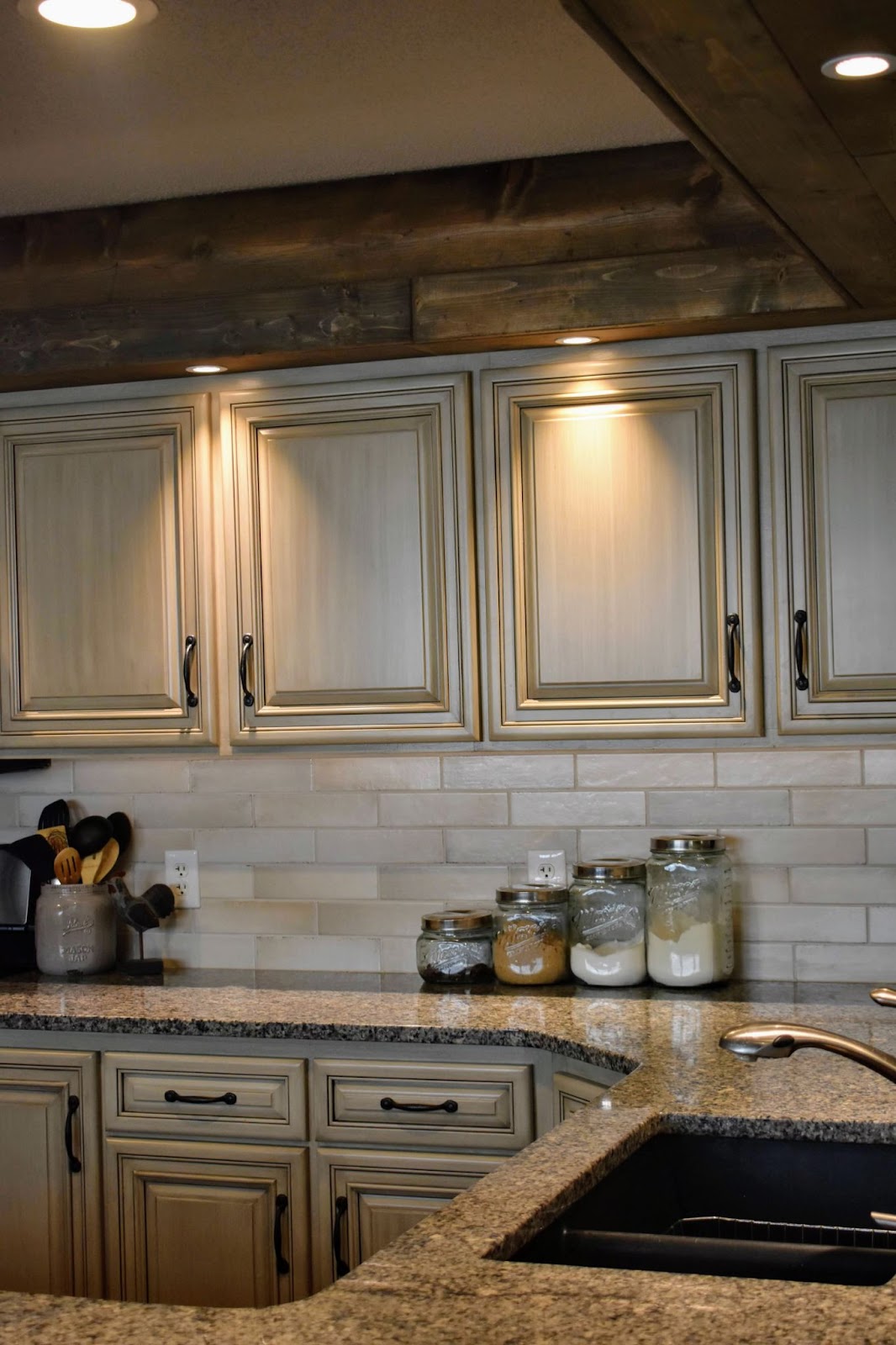 Warm-white, glazed and smooth kitchen cabinets with warm granite countertops and backsplash.