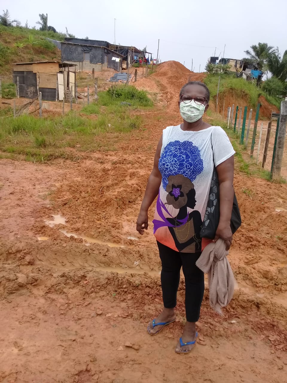 Dona Mira Alves, mulher negra, dirigente do MSTB, em pé no chão de barro de uma ocupação por moradia.