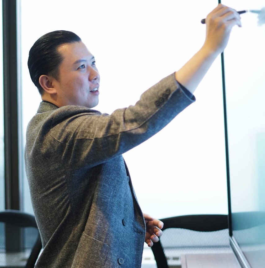 Dan Lok is standing and writing on board- a picture illustrate his businesses and mindset