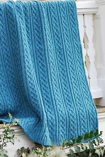 blue textured loom knit blanket hanging on porch railing