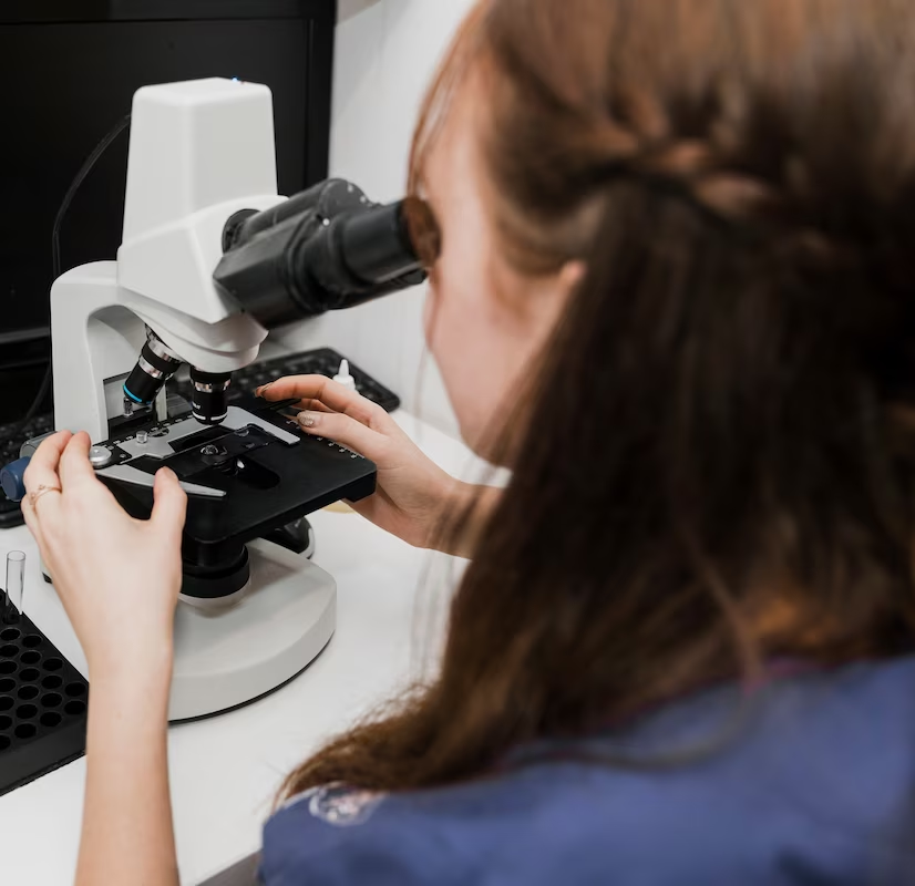 An optometrist peering through a microscope while conducting optical research.
