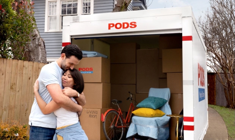 couple hugging in front of a loaded PODS moving & storage container