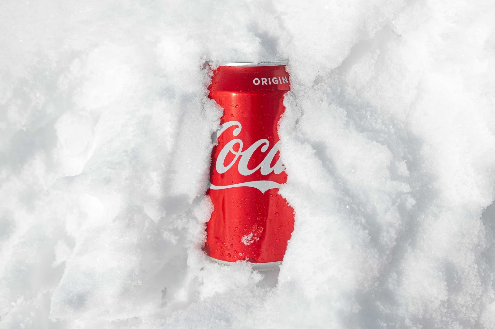 An image of a can of Coca-Cola buried in snow—only Coca is visible.
