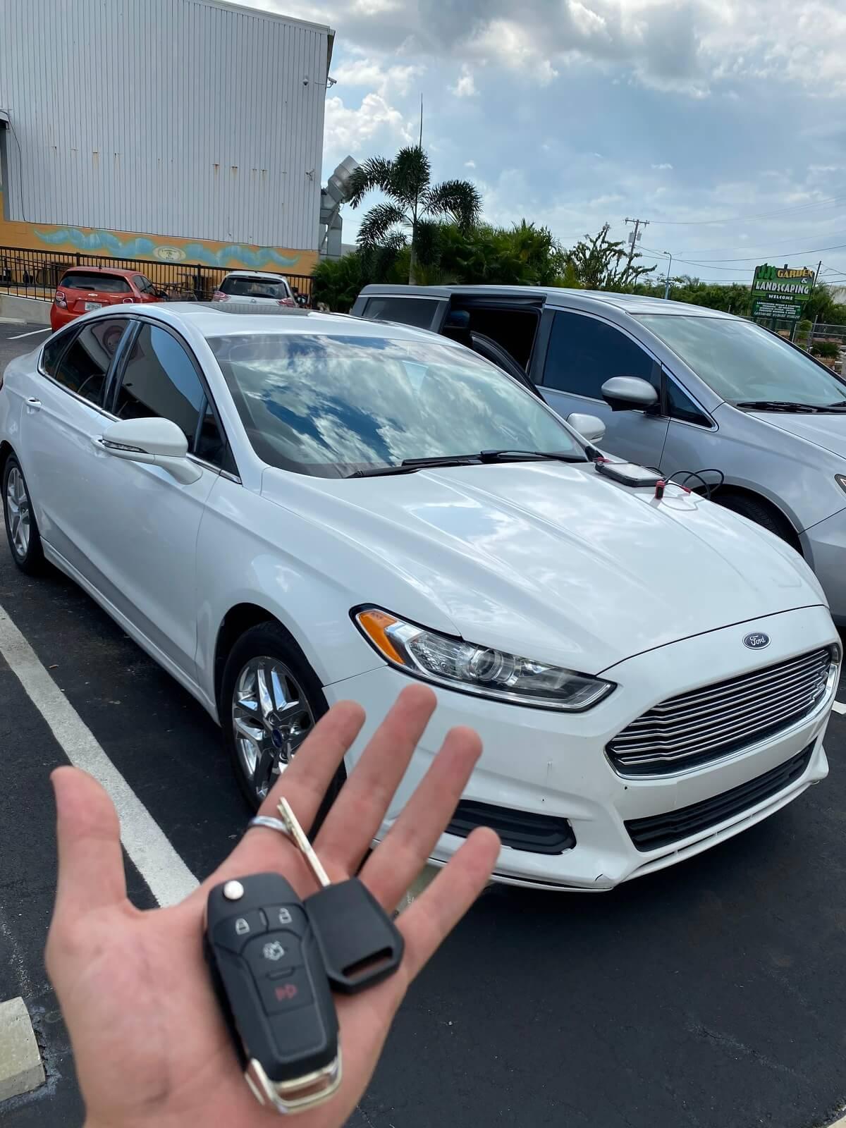 A hand holding a cell phone in front of a car

Description automatically generated with low confidence