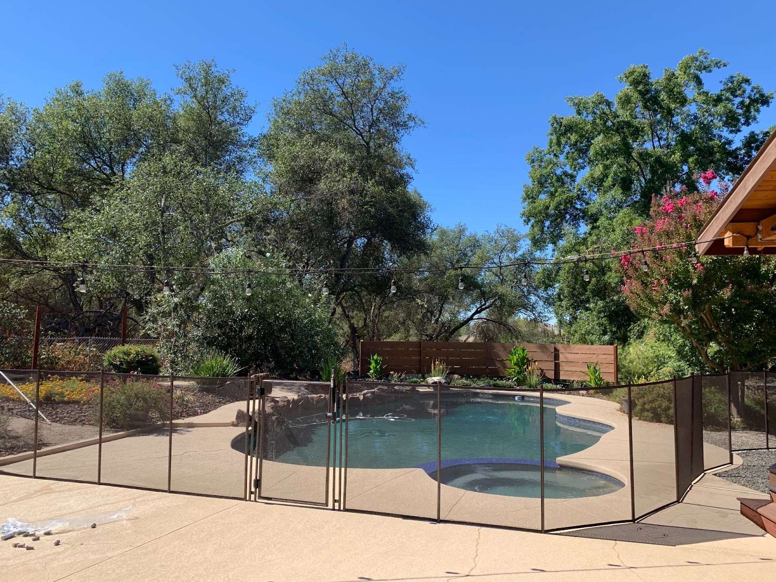 Brown mesh swimming pool fence installed around a residential pool