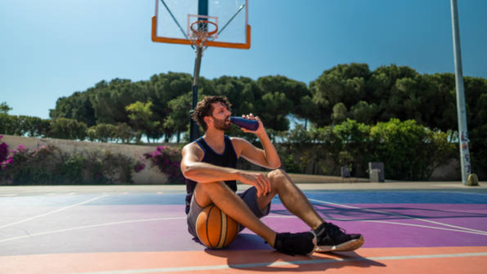 man drinking a pre-workout before playing basketball