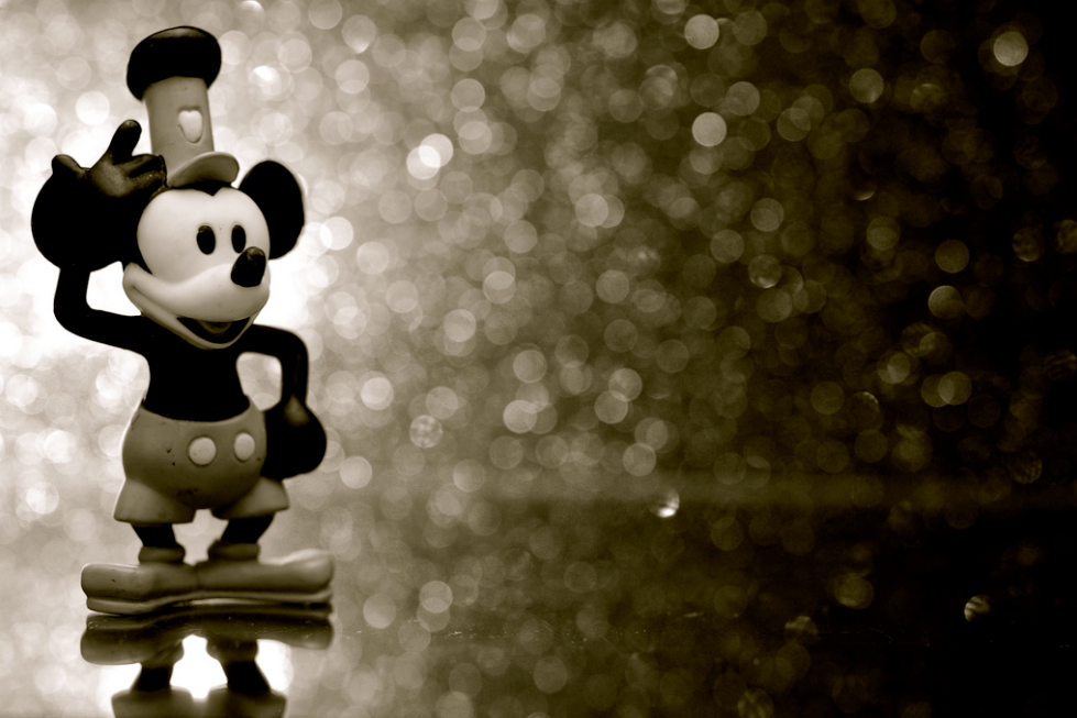 Mickey Mouse standing in front of a glittery background.