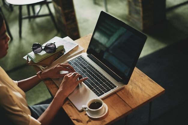 Foto grátis irreconhecível mulher asiática sentado no café e trabalhando no laptop
