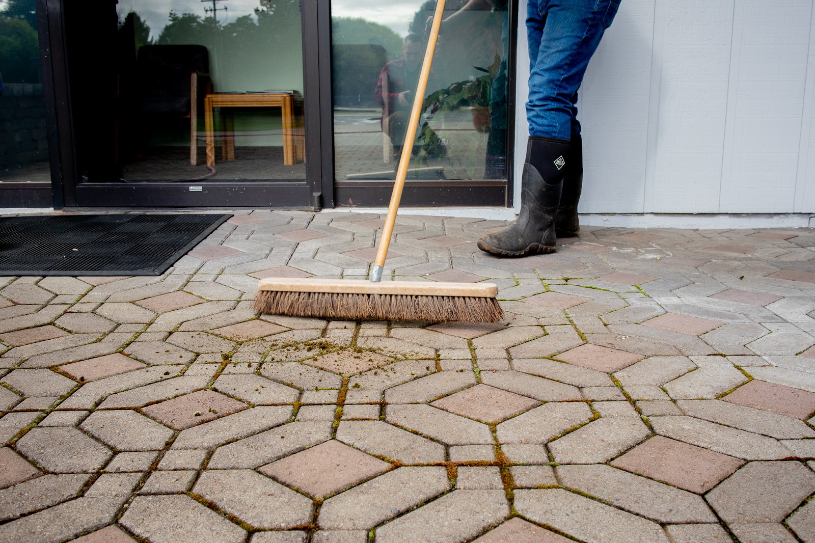 Sweeping away moss debris from paving stones.