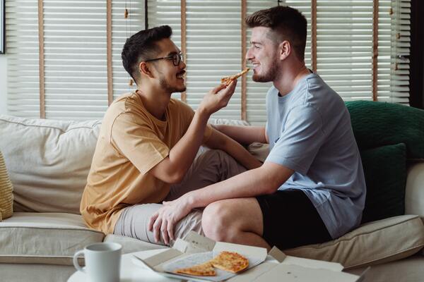 Foto de um casal gay comendo pizza