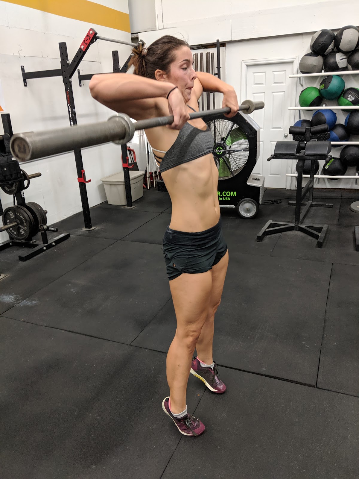 woman in gym doing a clean pull with barbell