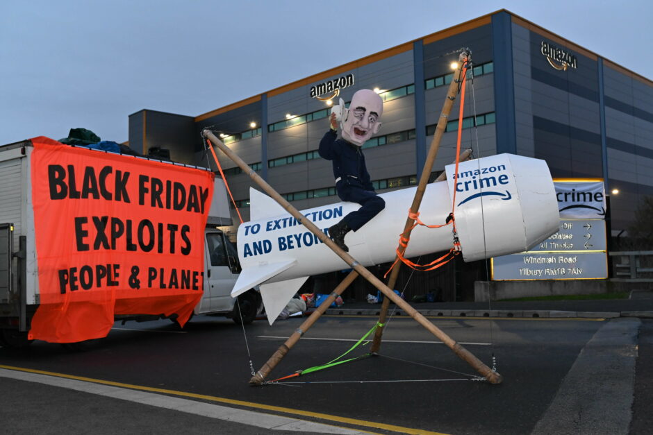 Black Friday exploits people & planet banner in front of Amazon warehouse