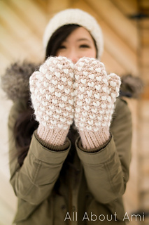 a lady wearing a bulky thrummed mittens with heart shape designs