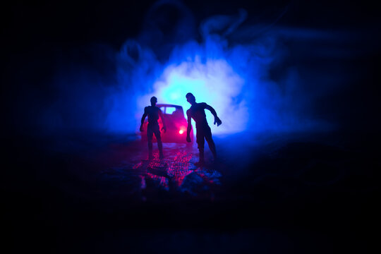 photo of a car stopped on the road lighting up a zombies. Silhouette terrible zombie night near the 