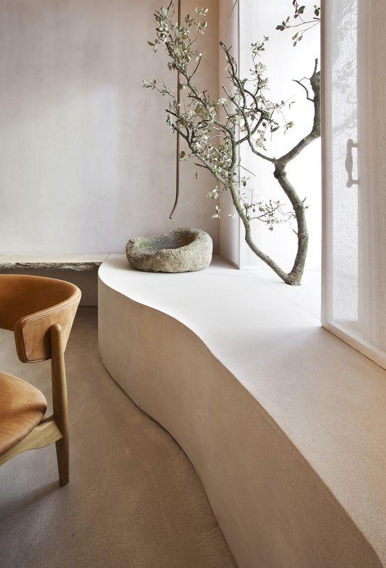 Ambiente com cores claras e elementos naturais como galho de arvore, cadeira de madeira.