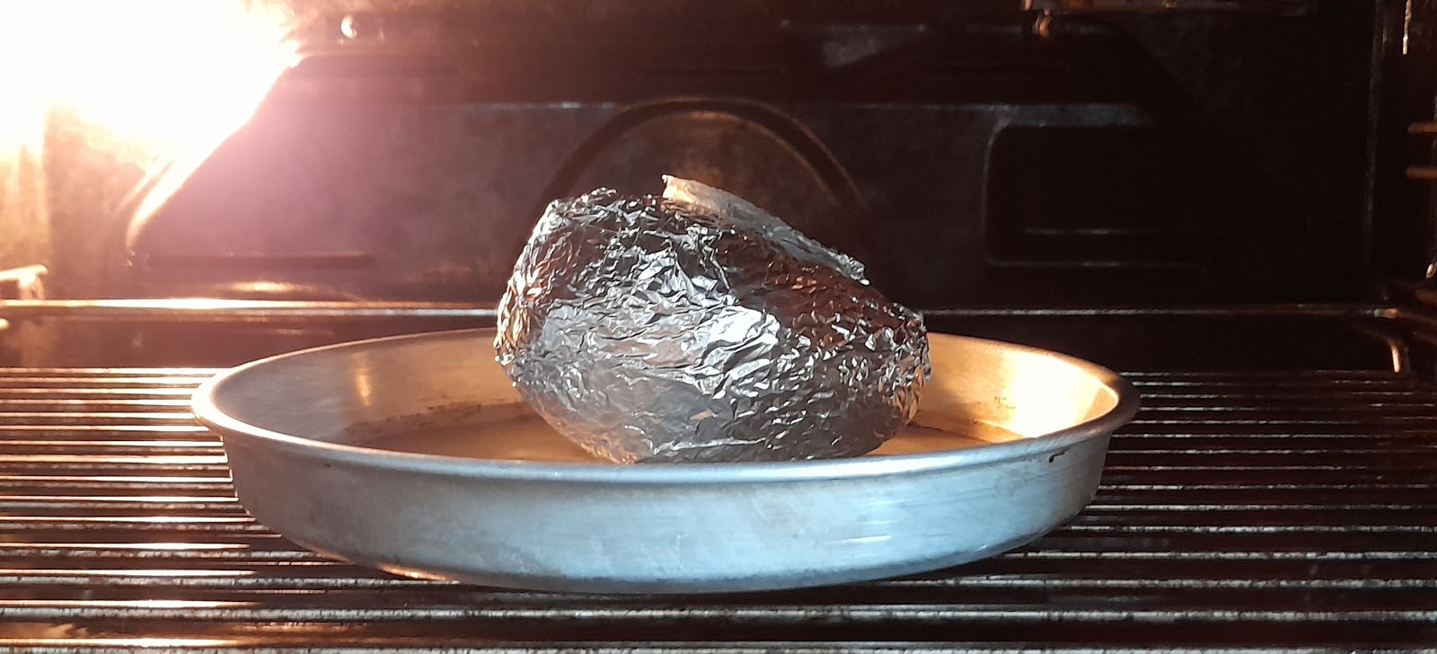 Avocado wrapped in aluminum foil in the oven.