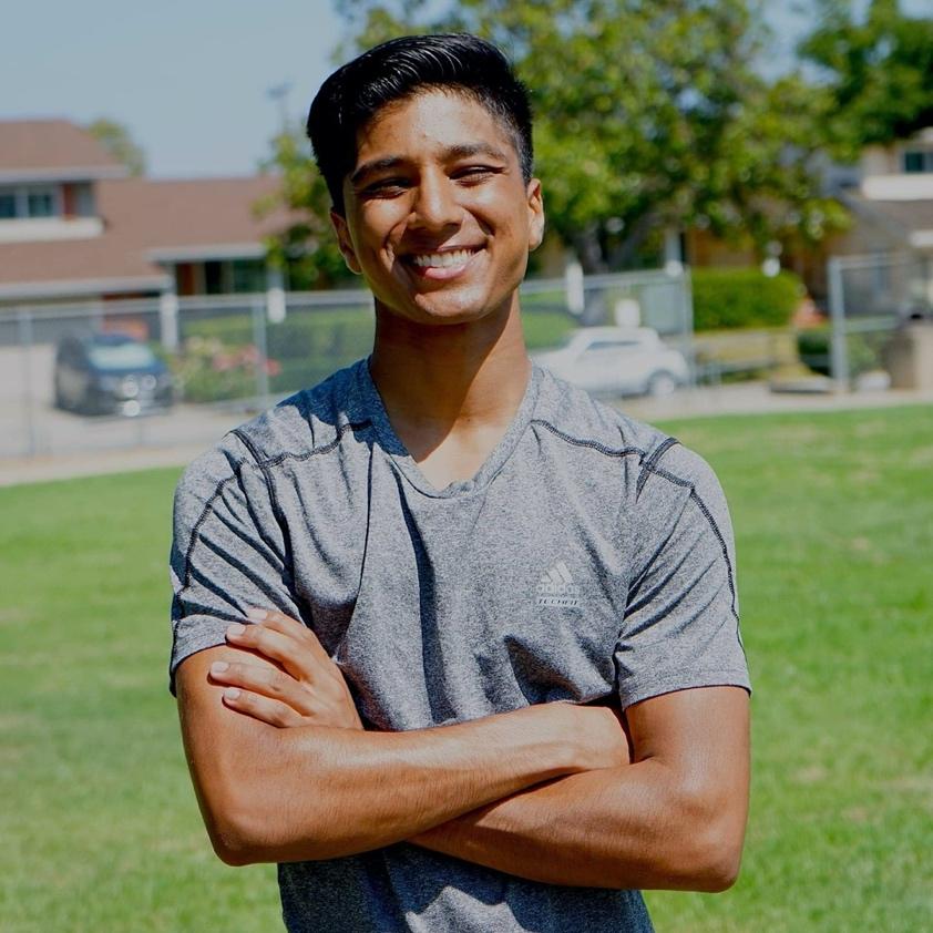 Student Samarth Dev smiling against the sun with his arms crossed.