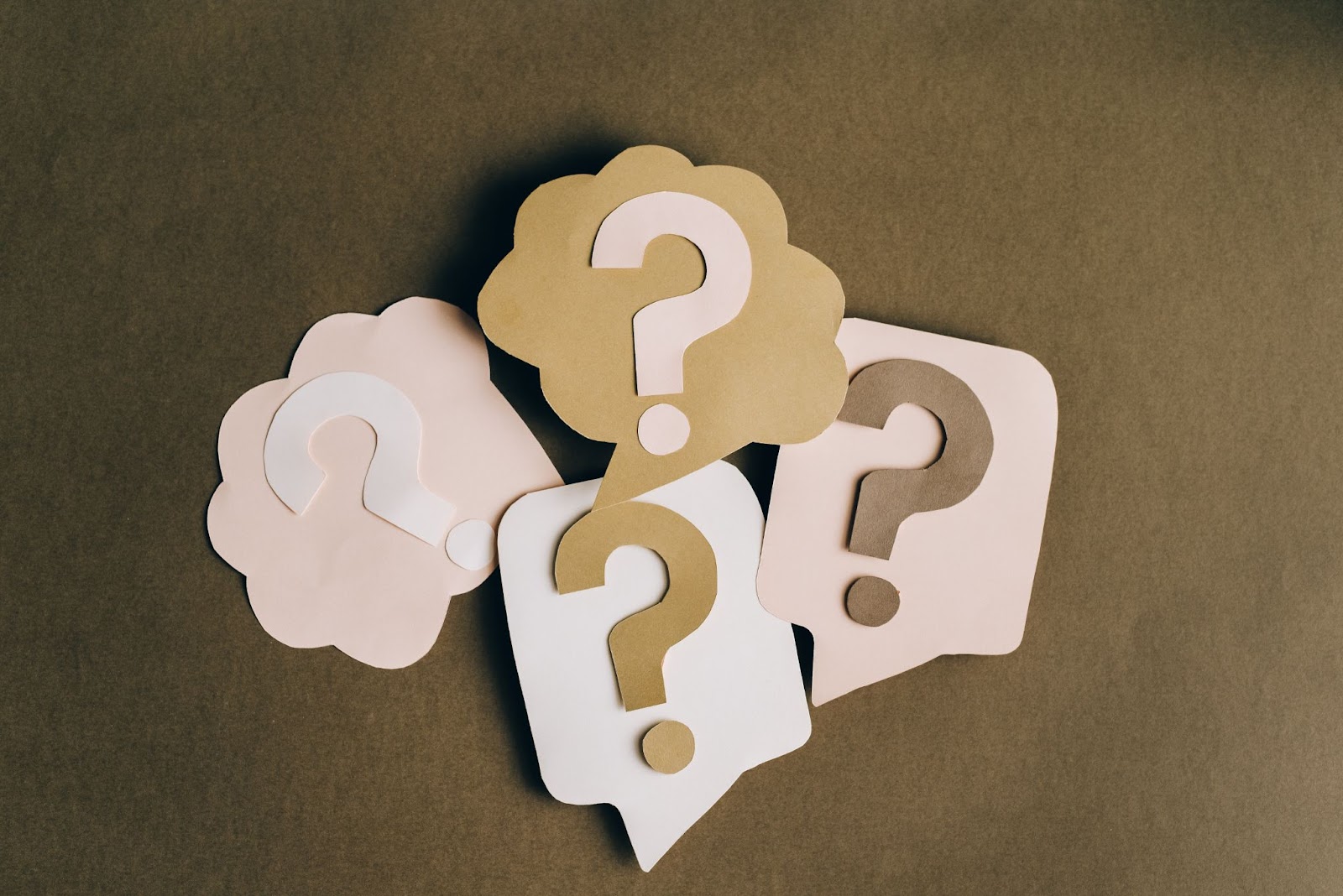 Paper cuttings of question marks against a brown background