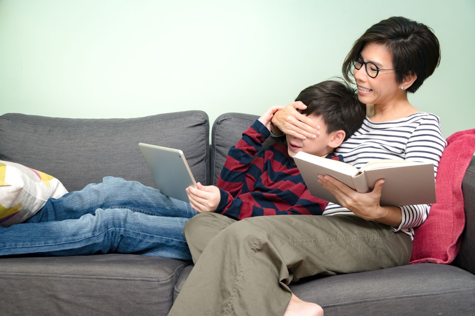 A mother covering her preteen son's eyes while online inappropriate content has show on tablet computer.