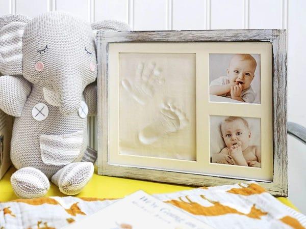 frame containing two photos of a baby and clay hand and footprint