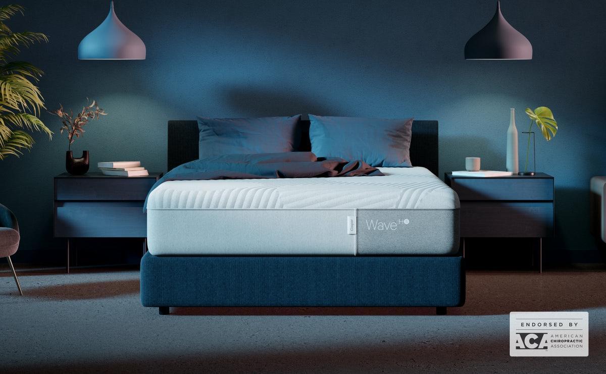 The Casper Wave Hybrid Snow Mattress is on a blue bed in a very blue room. Front view from the foot of the bed.