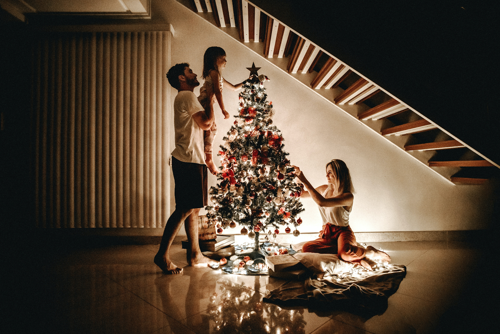 A young couple and their little girl decorating a Christmas tree