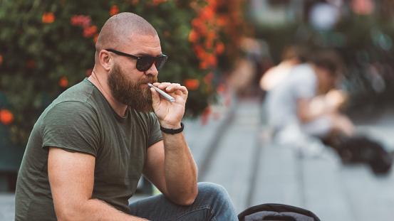 https://media.istockphoto.com/photos/young-bearded-man-is-sitting-in-the-park-in-amsterdam-and-smoking-or-picture-id1159567305?b=1&k=20&m=1159567305&s=170667a&w=0&h=ZeqcibeNnfFkyOgyPsfpeOS16-I9Aysd_4m77ZU9ST0=