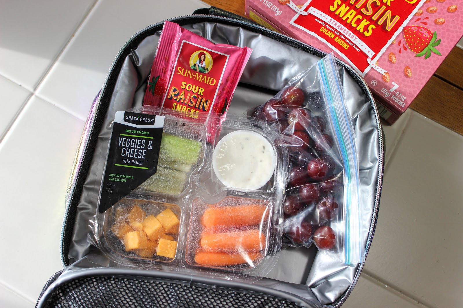 lunchbox with grapes and veggie and cheese tray with Sun-Maid Sour Raisin Snacks.