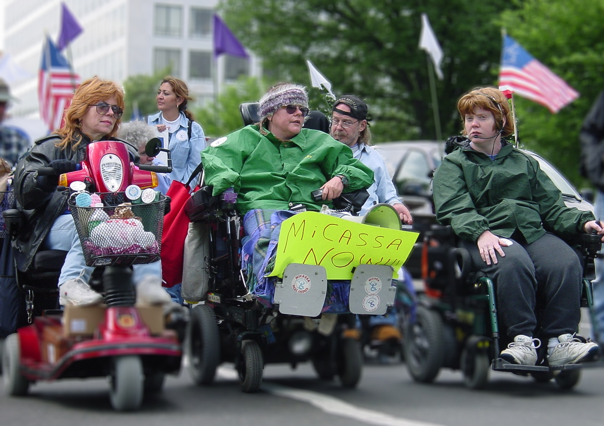 People using wheelchairs lead others in the street. 