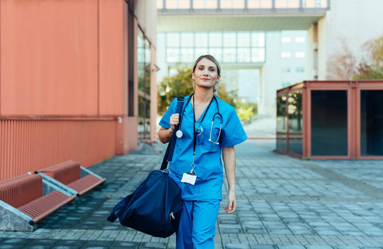 A person in blue scrubs walking down a sidewalk

Description automatically generated