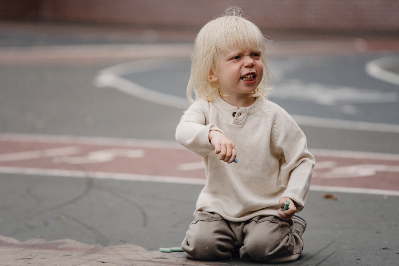 Child refusing to see parent in Australia. Grumpy toddler on asphalt court.