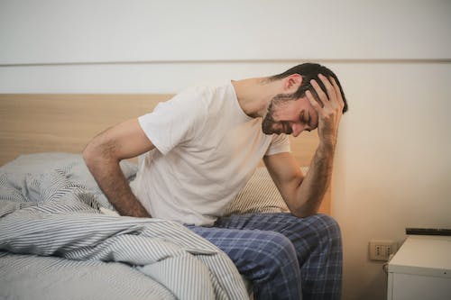 Free Young man in sleepwear suffering from headache in morning Stock Photo
