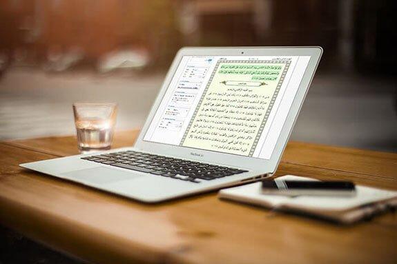 A cup of water and a laptop that shows a Surah 