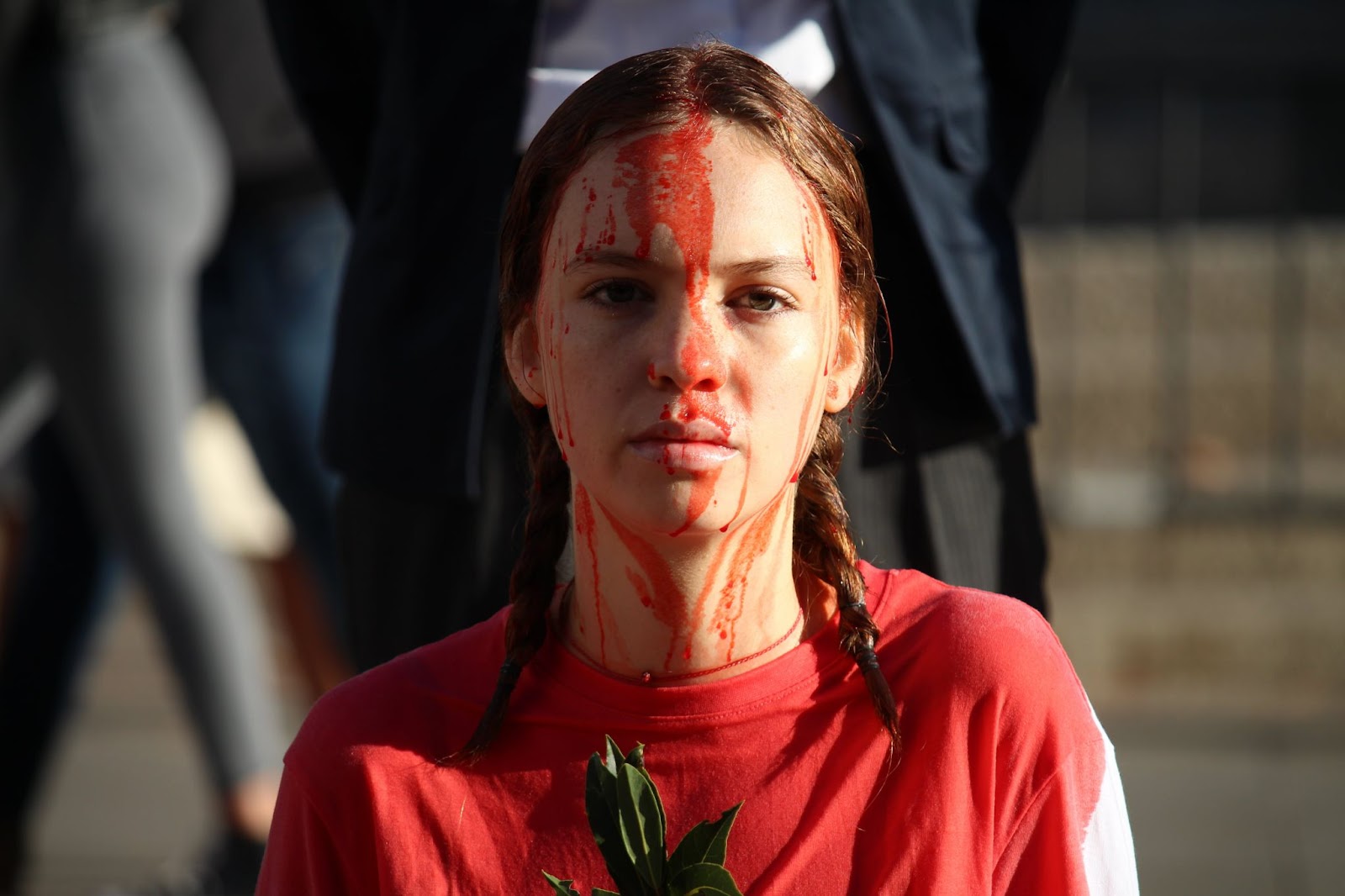 A young woman rebel looks to camera sadly. Fake blood has been poured down her face.