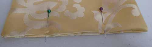 Two pins hold the opening to the cream silk linking in place with the unfinished edge folded in.