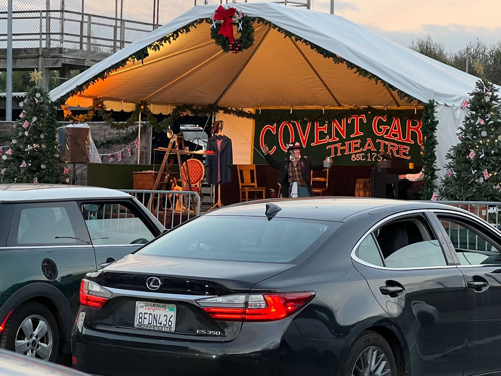 Cars sit parked in front of a stage that displays part of a sign that reads "Covent Garden Theatre."