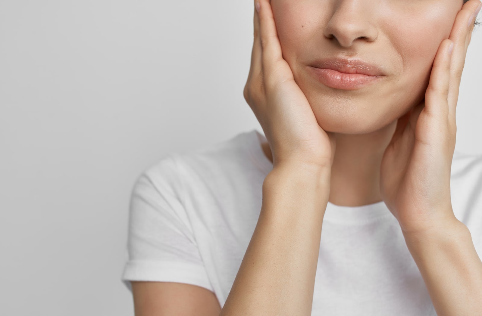 A woman holding the bottom of her face due to mouth pain