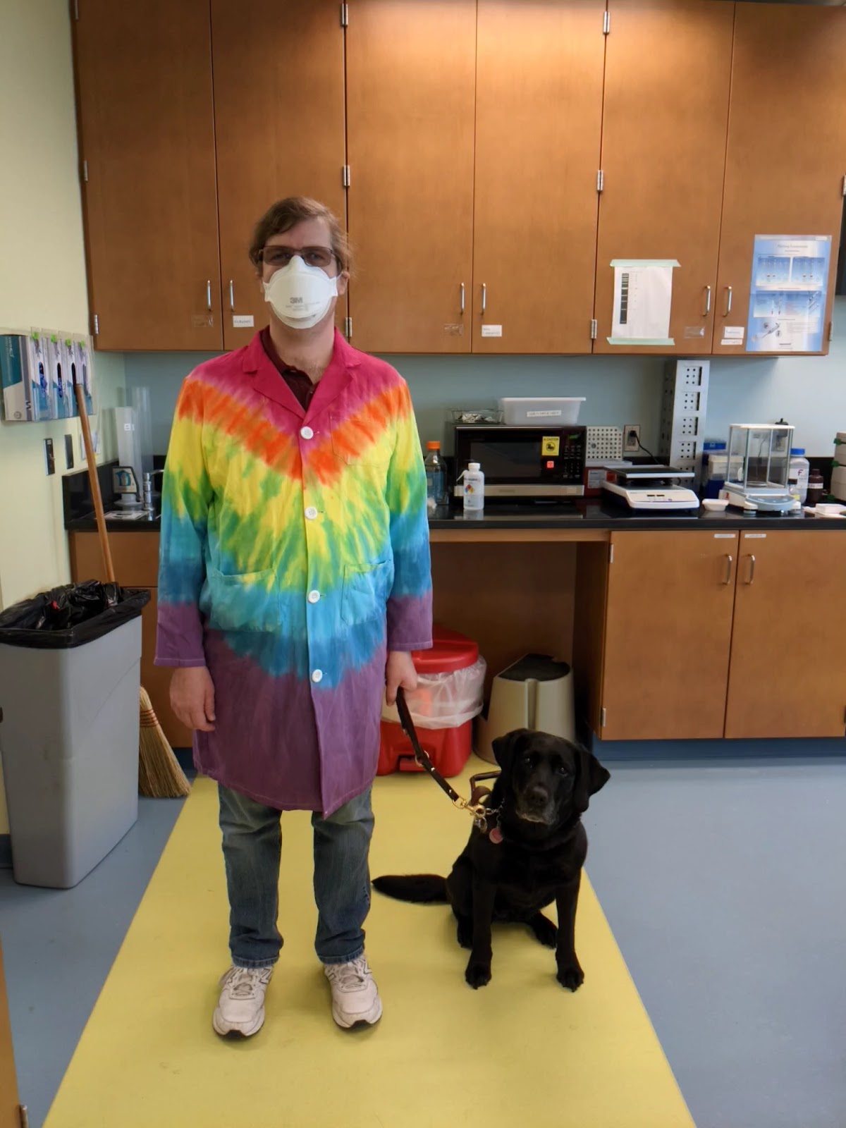 Dr. Hasley wearing tie-dye lab coat with service dog Shade 