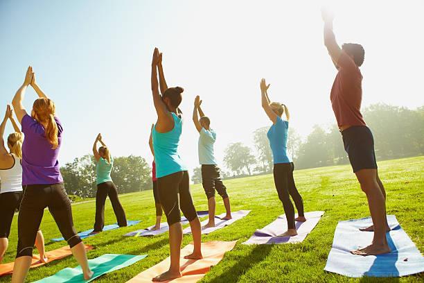Body, mind and soul Young group of sportspeople taking a yoga class outdoors yoga class stock pictures, royalty-free photos & images