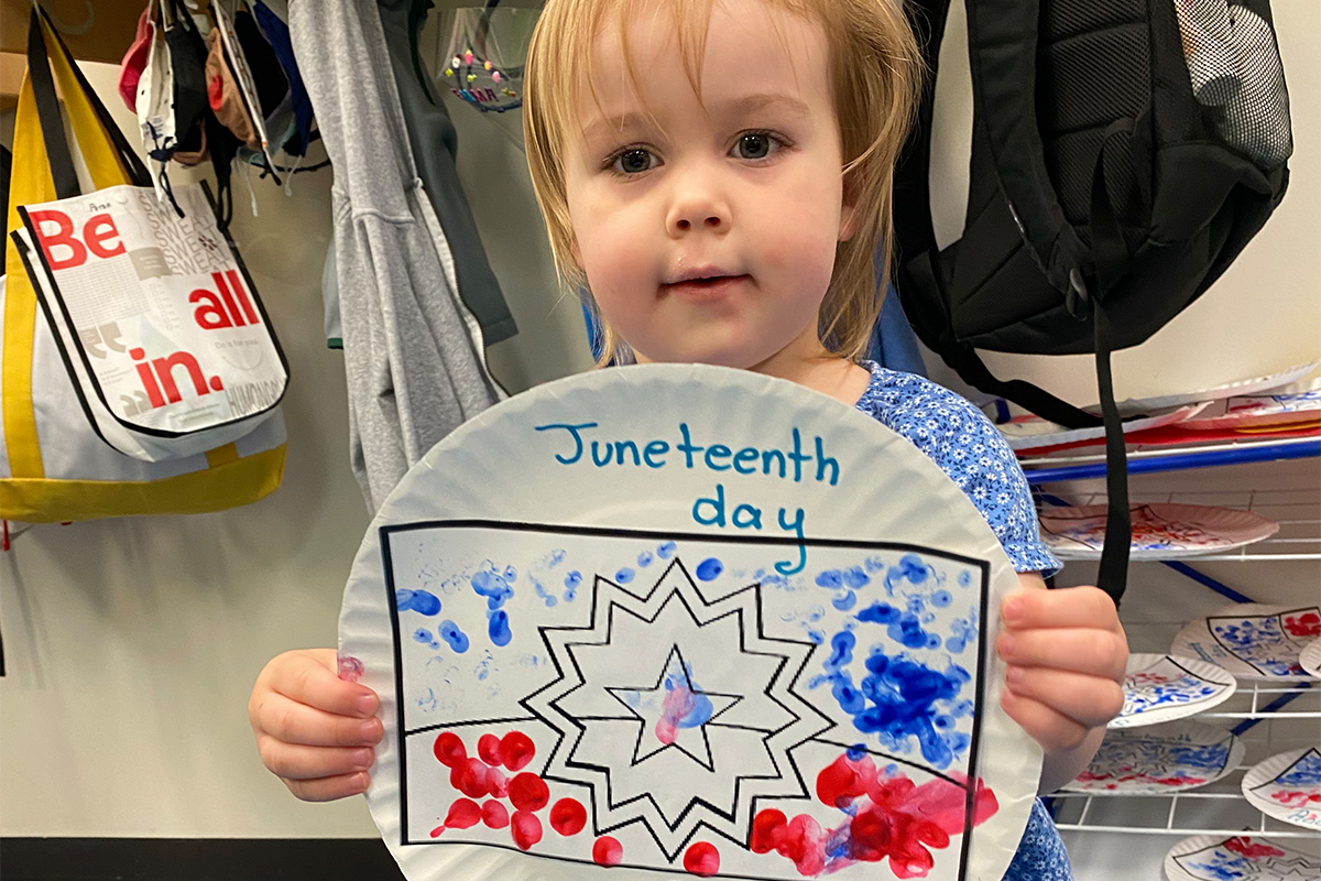 child holding up their juneteenth art project