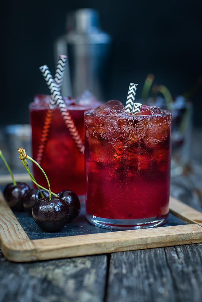 Cocktail served on the rocks garnished with cherries