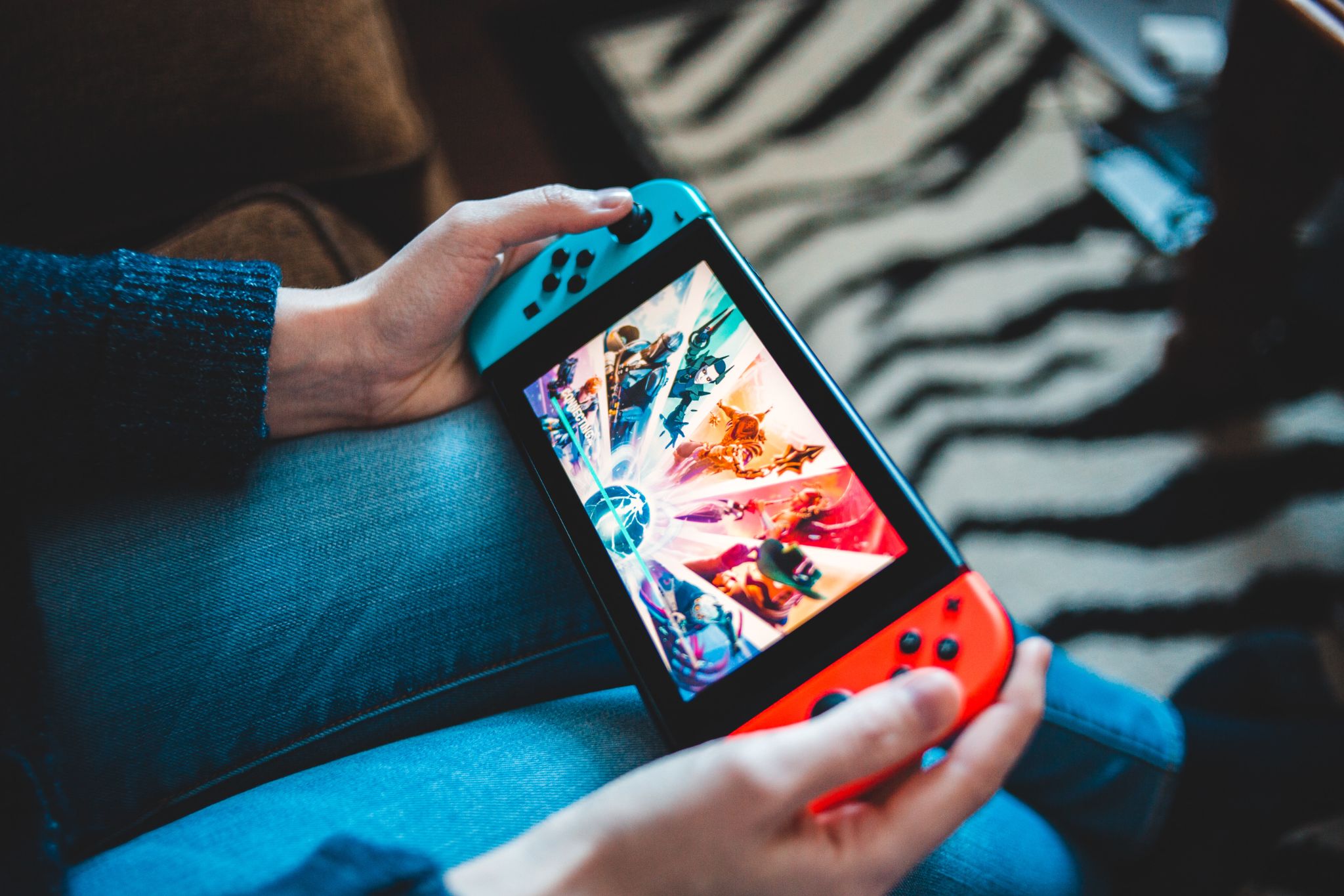 A woman plays a game on a Nintendo Switch handheld gaming console.