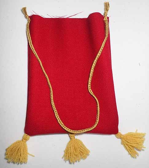 The other layer of a red wool bag with three gold tassels, top edge unfinished, with a matching gold cord secured on the left and right sides for hanging on a belt.